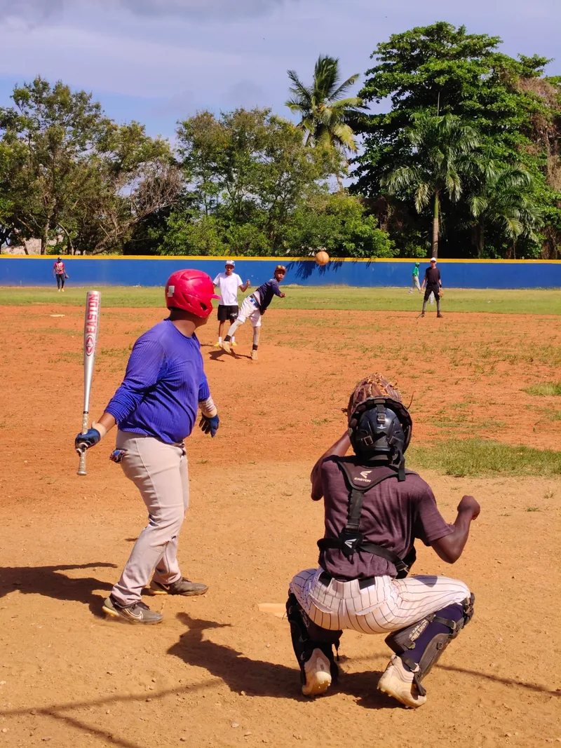 Jóvenes entrenando béisbol en un campo de barrio